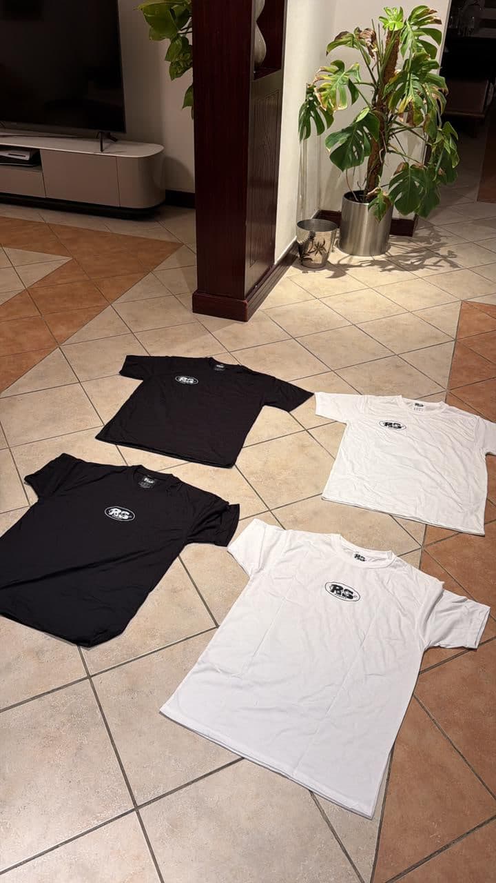 Two black and two bone tees laid out front side up, oval chest logo showing